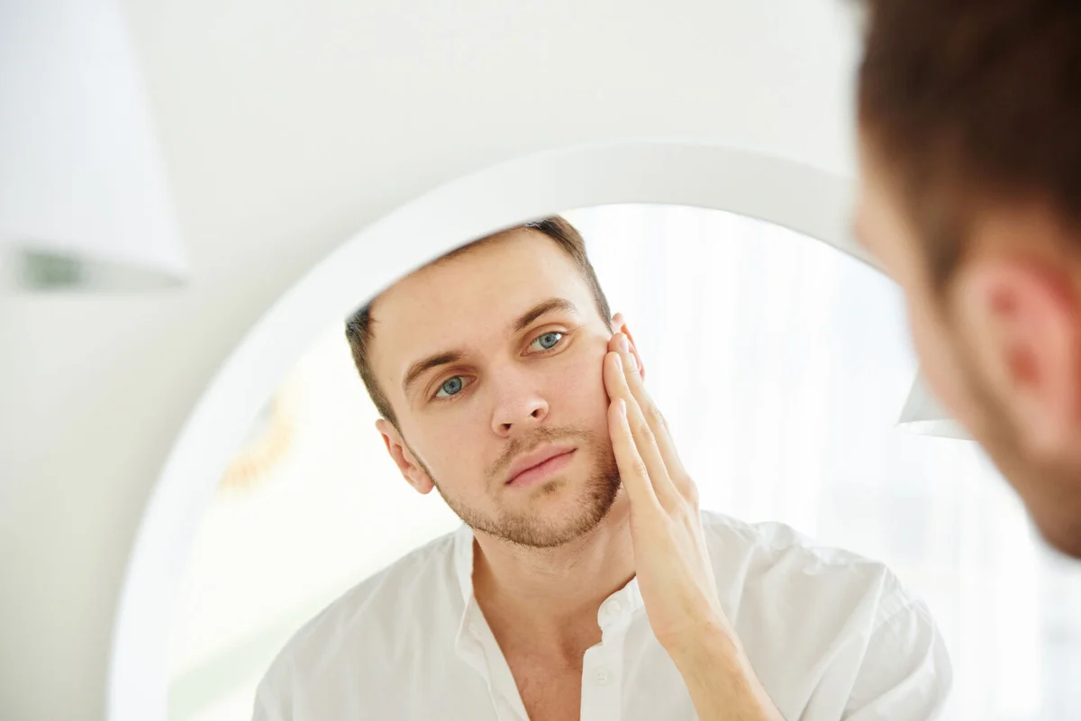 Man-with-facial-looking-at-mirror